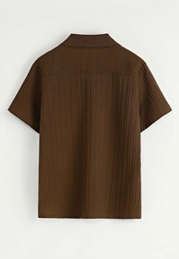 Chemise marron à manches courtes avec une texture à côtes verticales et un large col pointu, vue de dos sur un fond blanc uni.