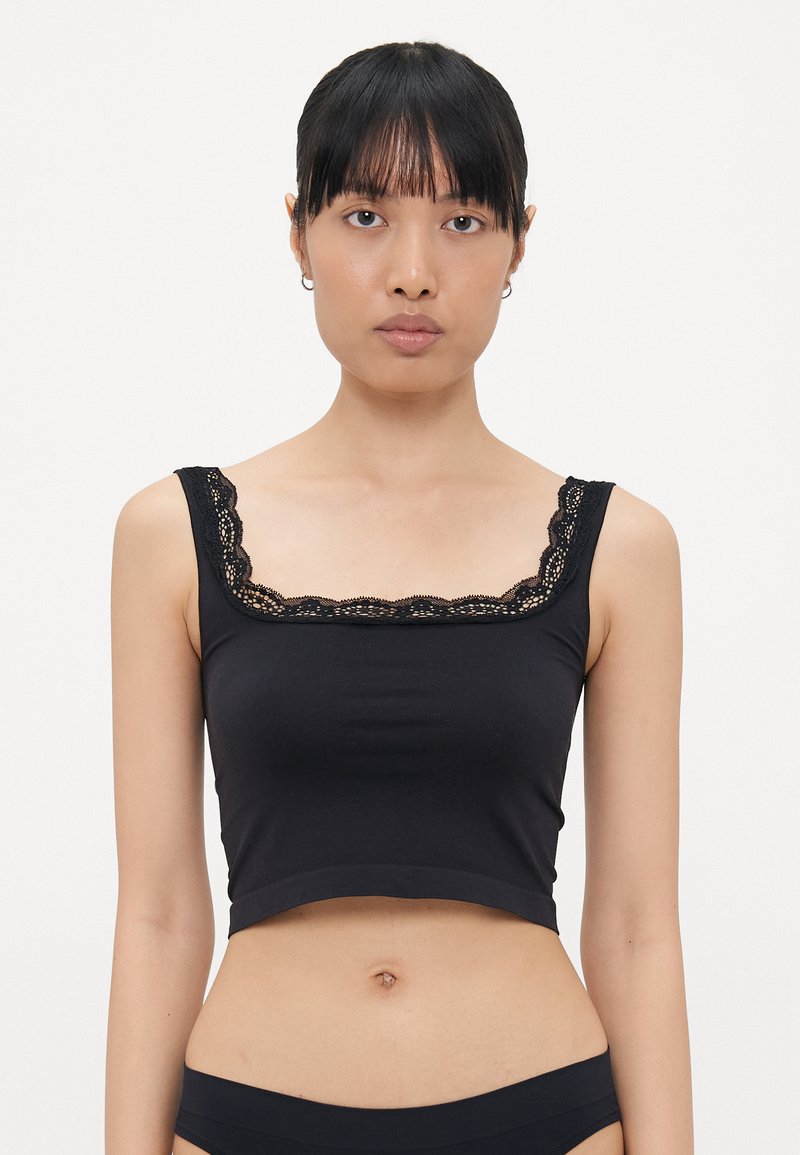 Zwart crop top van zachte stof, met een vierkante halslijn met delicate kantafwerking en brede schouderbanden. Gladde textuur en aansluitend ontwerp.