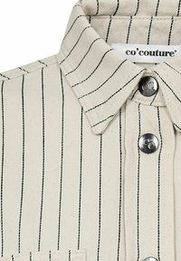 Beige Hemd mit schwarzen senkrechten Streifen, ausgestattet mit einem Kragen, Metallknöpfen und einer genähten Taschenapplikation. Markenetikett sichtbar.
