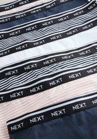 Five pairs of boxer briefs with contrasting colors: navy, white, peach, and striped patterns, featuring a black elastic band with "NEXT" logo.