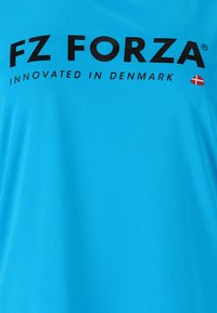 Blå tyg med fet svart text "FZ FORZA" och mindre text "INNOVATED IN DENMARK" tillsammans med en liten röd och vit dansk flagga.