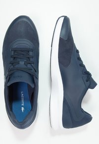 Sportovní boty Lacoste v tmavě námořnické modři. Obsahují síťované a syntetické materiály, kulatou špičku, polstrovaný jazyk, bílou mezipodešev a značkovou stélku.