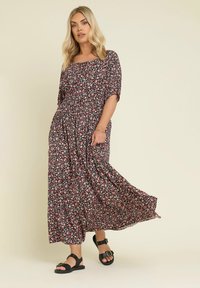 Blommig maxiklänning i svart tyg, med korta ärmar, en figursydd midja och en svängande kjol med rosa och vita blommönster.