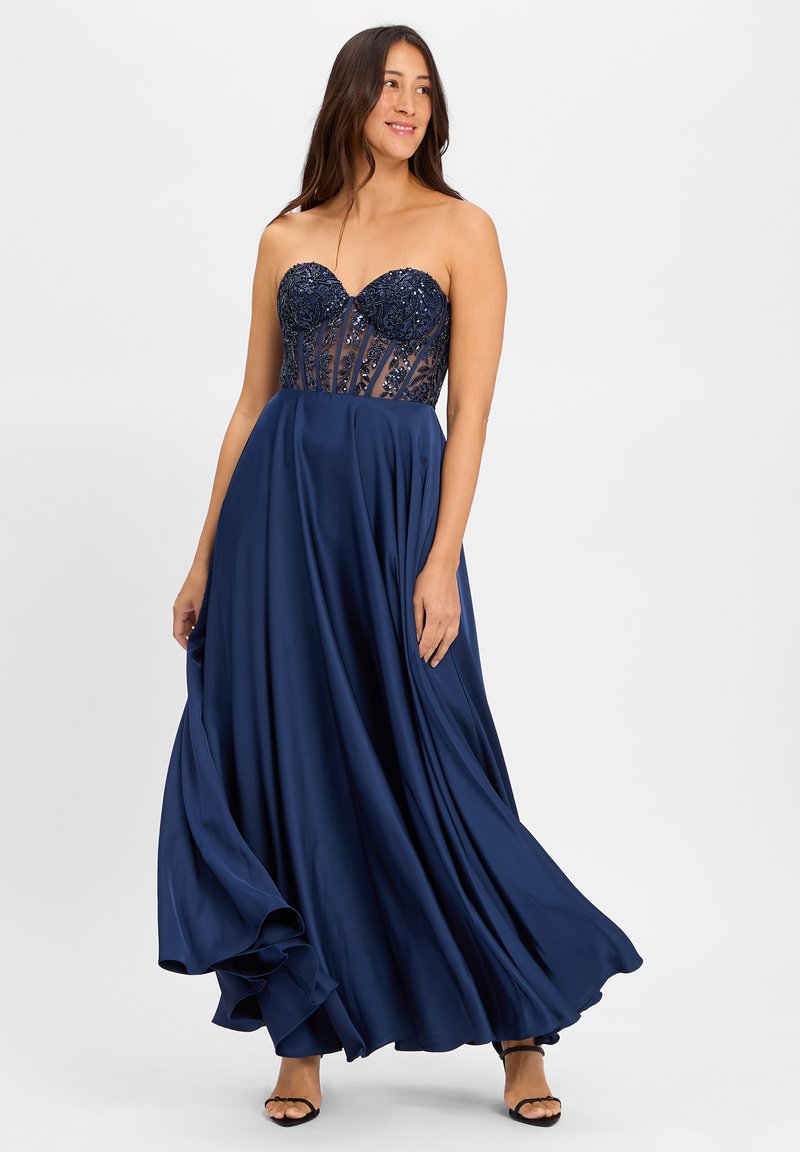 Robe de soirée bleu marine avec un corsage sans bretelles orné de sequins décoratifs, jupe fluide et texture satinée.
