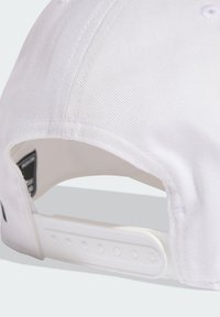 Gorra blanca con tejido texturizado, visera curva y correa ajustable de plástico con múltiples ranuras de tamaño para un ajuste seguro.