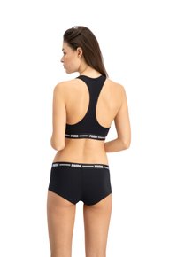 Zwarte sportbeha met een racerback ontwerp en elastische band met het Puma-logo. Gekocht met bijpassende zwarte shorts met een geborduurd logo op de tailleband.