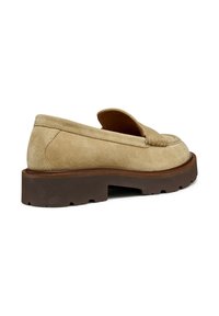 Mocasín de ante beige con una suela plana de goma marrón texturizada. Presenta un detalle de costura en la punta y un diseño tradicional de fácil uso.