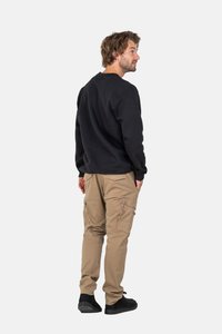 Schwarzer Sweatshirt mit Rundhalsausschnitt, kombiniert mit beigen Cargo-Hosen mit mehreren Taschen. Die Schuhe sind schwarz.