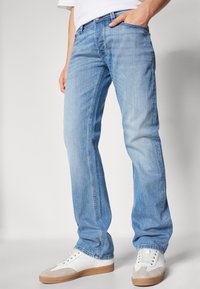 Ljusblå denimjeans med rak passform, med subtila blekningar och fem fickor. I kombination med vita sneakers och en enkel skjorta.