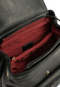 Zwarte leren rugzak met een kastanjesatureren interieur. Meerdere rode ritszakken en een gouden hardware detail zichtbaar.