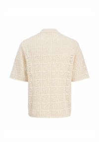 Κρεμ κοντομάνικη πλεκτή μπλούζα με ανοιχτό σχέδιο πλέξης και ριμπ λαιμόκοψη, εμφανίζεται από πίσω.