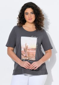 Donkergrijze t-shirt met korte mouwen, voorzien van een kleurrafisch van de woestijn en de tekst "Eindeloze Dagen van Zomer" in het wit. Zacht materiaal.