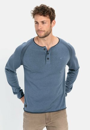 Lange mouwen blauwe henley-shirt gemaakt van zacht materiaal met een ronde hals, een drie-knops placket en ribbelaccenten langs de schouders.