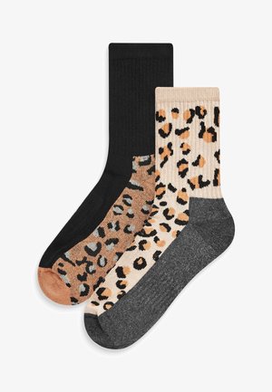 Kaksi paria sukkia: toiset kokonaan mustat ribbikuvioiset, ja toiset beige leopardikuvioilla, joissa on ruskeita ja harmaita yksityiskohtia.