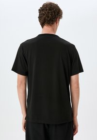 Sort bomulds T-shirt med korte ærmer og rund hals. Glat tekstur og lige afslutning. Minimalistisk design uden synlige logoer eller mønstre.