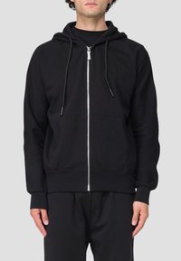 Felpa con zip nera realizzata in tessuto morbido, dotata di cappuccio, cordini regolabili e tasche frontali. Design minimalista con polsini a costine.