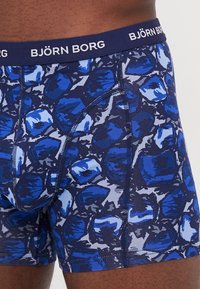 Boxer shorts with a blue and gray abstract pattern, made of soft fabric. Features a navy waistband labeled "BJÖRN BORG."