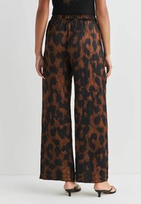 Szorty z pomarszczonego materiału w szerokim kroju, w brązowo-czarny wzór w panterkę, z elastyczną talią i luźnym fasonem.