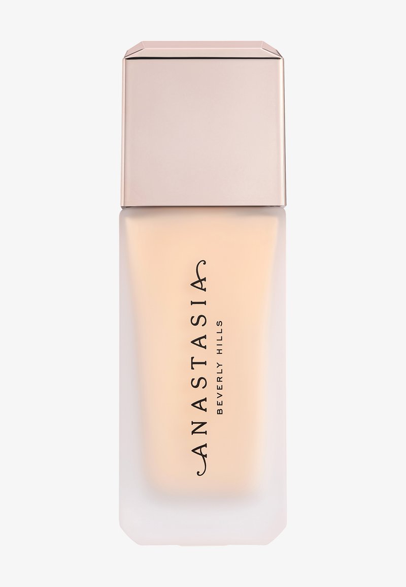Flacon de fond de teint avec corps en verre dépoli et bouchon en or rose, étiqueté « Anastasia Beverly Hills » en texte noir vertical.