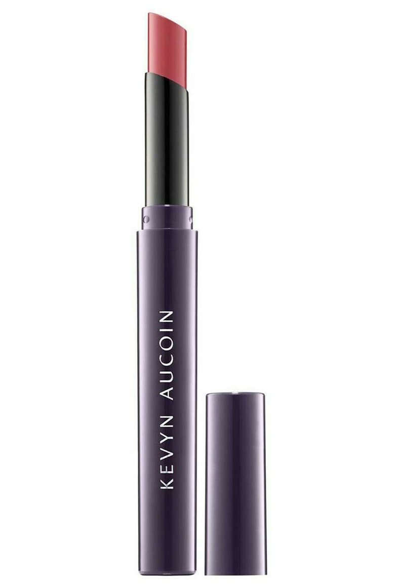 Lippenstift in einer schlanken, lila Tube mit einem schwarzen Deckel. Die Farbe ist ein sanfter rosafarbener Ton und hat eine geschwungene Spitze für eine präzise Anwendung.