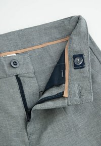 Szare, tkane spodnie z zamkiem błyskawicznym i zapięciem na guzik. Wnętrze wykończone jest jasnobrązową podszewką z granatowym akcentem oraz widocznymi detalami szwów.