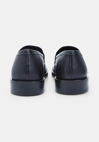 Pantofi din piele neagră, cu vârf rotunjit, textură netedă, toc mic și detalii de cusătură minime, văzuți din spate.