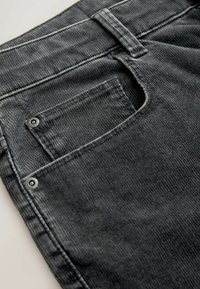 Mustad mustriga püksid, millel on selja taga tasku, kus on tugevdatud avaus ja metallist nupukinnitus. Kude on sooneline ja pehme.