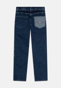 Ciemnoniebieskie dżinsy o prostym kroju. Posiadają dwie tylne kieszenie, z których jedna w kontrastującym jasnoniebieskim kolorze z trójkątnym logo.