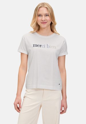 Witte katoenen t-shirt met korte mouwen en een ronde hals. De tekst op de voorkant zegt "merci bien" in verschillende tinten grijs en blauw.