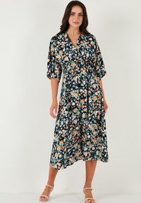 Floral midi dress in dark navy, featuring a v-neck, short sleeves, and an elastic waist. The fabric is lightweight with a smooth texture.