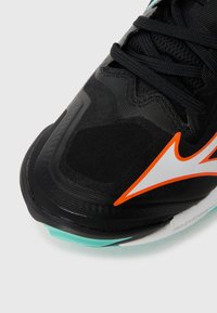 Black athletic shoe with textured upper, orange logo accent, and aqua sole. Features minimalistic design with prominent lacing system.