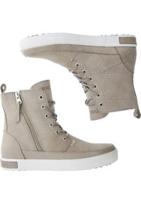 Beige canvas enkellaarsjes met een textuurafwerking, witte rubberen zool, vetersluiting aan de voorkant en een ritsdetail aan de zijkant. Bevat een subtiel merkembleem aan de zijkant.