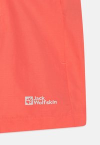 Shorts d'extérieur de couleur corail en tissu léger. Logo Jack Wolfskin imprimé en blanc dans le coin inférieur gauche.