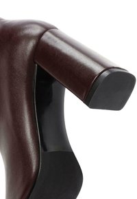 Scarpa con tacco alto caratterizzata da una parte superiore in pelle bordeaux lucida, un tacco spesso a blocco e una suola in gomma nera strutturata.