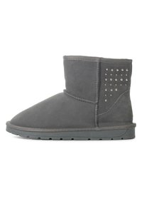 Botas de ante gris a nivel de tobillo, con puntera redondeada, que cuentan con un panel lateral adornado con tachuelas metálicas y una suela de goma texturizada.