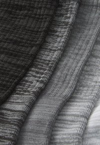 Gradient knit textile in shades of black, gray, and white, featuring varying textures and patterns across the fabric's surface.