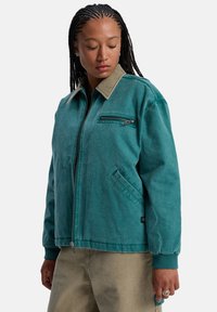 Teeal canvas jack met een contrasterende beige kraag, ritsluiting aan de voorkant en zijzakken. Voorzien van een zipped borstzak en geribbelde manchetten.