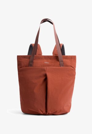 Sac fourre-tout couleur rouille avec deux poches avant, poignées marron et bretelles rembourrées, conçu pour un transport polyvalent.