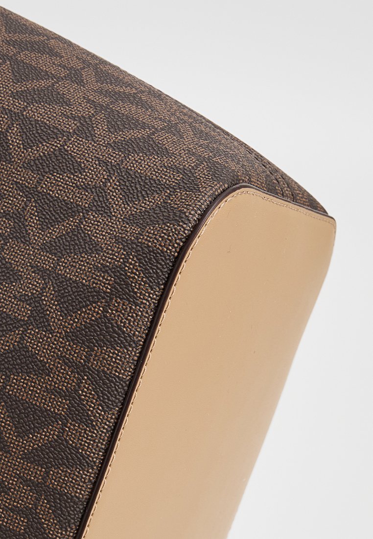 Bruine stof handtas met een gestructureerd, geometrisch ontwerp. Heeft een gladde beige leren basis en gestikte details.