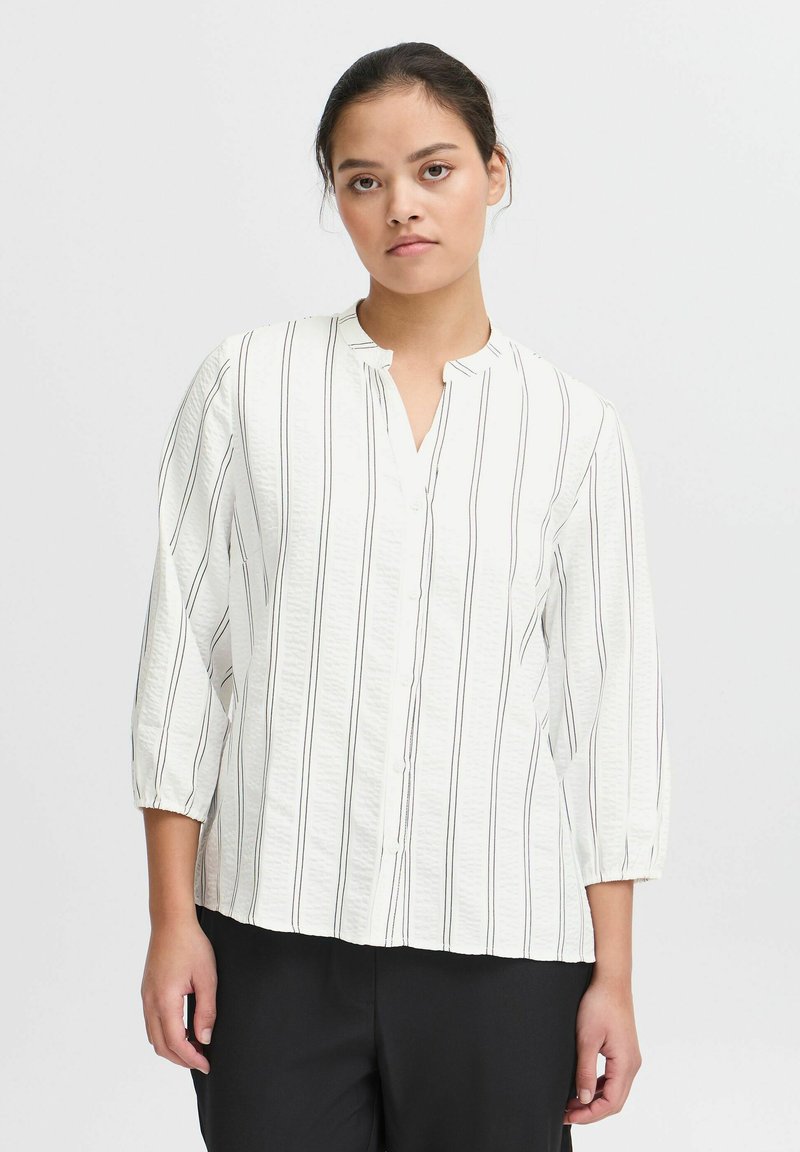 Witte button-up shirt met verticale zwarte strepen, voorzien van een Mandarin-kraag en driekwartmouwen, gemaakt van lichte, gestructureerde stof.