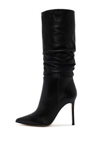 Bota de cuero negro de tacón alto con puntera afilada, caña despeinada y silueta estilizada. Presenta un tacón de aguja y una textura suave.
