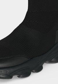 Μαύρο sneaker σε στυλ κάλτσας με υφασμένο άνω μέρος με υφή και χοντρή κυματιστή σόλα με διαφανή στοιχεία απορρόφησης κραδασμών.