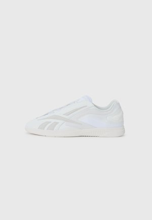 Zapatillas deportivas blancas con un upper texturizado, que presentan un diseño liso, franjas laterales prominentes y una suela de goma con patrón.