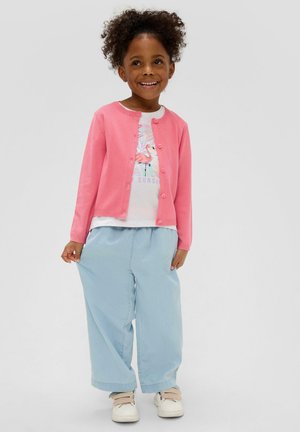 Pink cardigan over a white t-shirt with a flamingo graphic, paired with light blue wide-leg pants and white sneakers with straps.