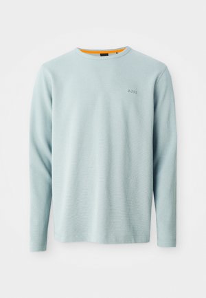 Világoskék, hosszú ujjú póló, texturált anyagból készült, kerek nyakkivágással. Az elején diszkrét logó található, a gallér belső részén narancssárga részlet látható.