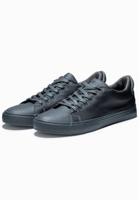 Grå sneakers med en texturerad tygöverdel, rund tå och gummisula. Funktioner inkluderar platta snören och förstärkta ögla för hållbarhet.