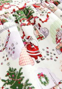 Baumwollstoff mit festlichem Muster, das Santa, Weihnachtsbäume, Geschenke und Sterne zeigt, überwiegend in Rot, Grün und Weiß.