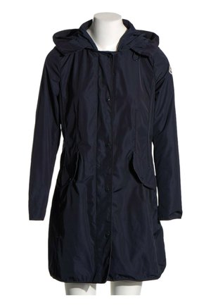 Impermeable largo azul marino oscuro con capucha, botones delanteros, bolsillos con solapa y un pequeño parche con logo en la manga izquierda, mostrado en un maniquí blanco.