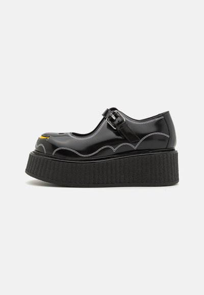 Pantofi cu platformă din piele patent neagră, cu design scallopat, cusături albe și cataramă. Talpă groasă texturată, vârf rotund.