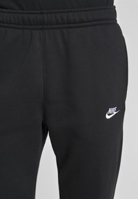 Svarta joggingbyxor i mjuk bomullsblandad väv. Utrustade med elastisk midja och en liten vit Nike-logotyp på vänster lår.
